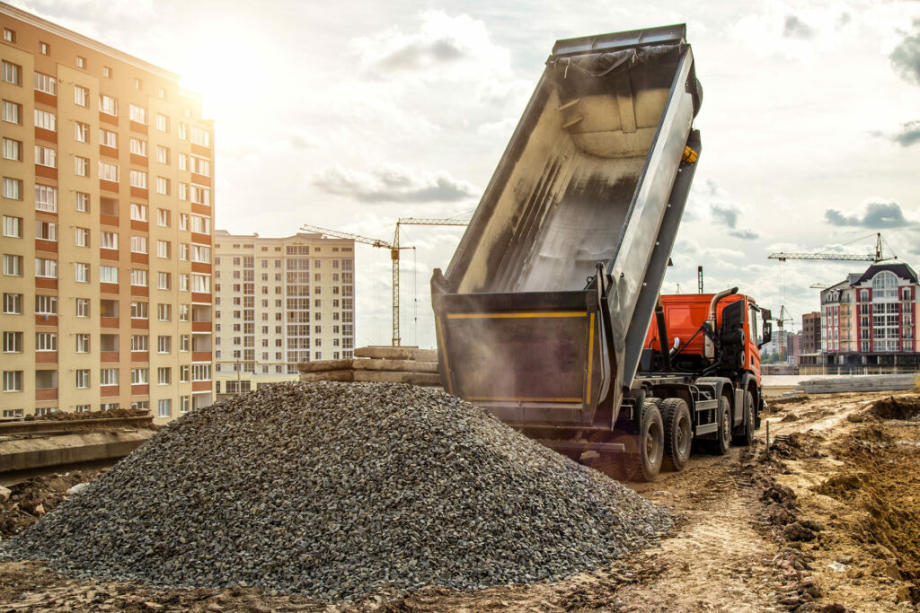 Construction truck tipping dumping gravel on road construction site,tip truck and ripper at work preparing ground for new housing estate,Dump truck unloading process,